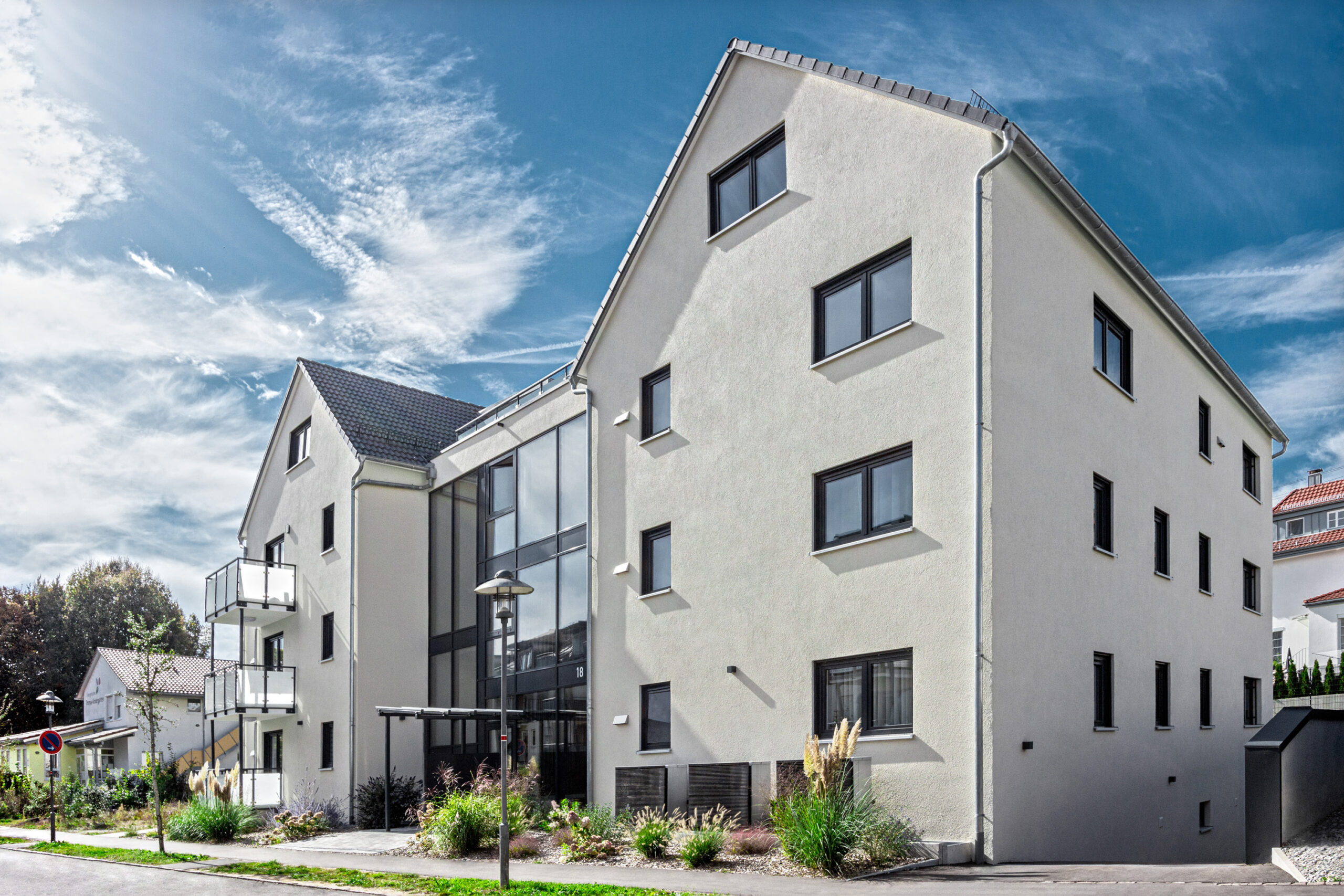 Foto neues Mehrfamilienhaus, Aufnahme leicht seitlich, Spätsommer, blauer Himmel