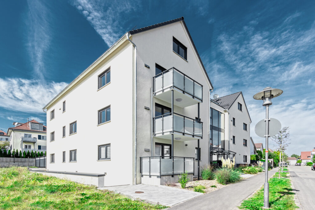 Foto neues Mehrfamilienhaus, Aufnahme leicht seitlich, Spätsommer, blauer Himmel